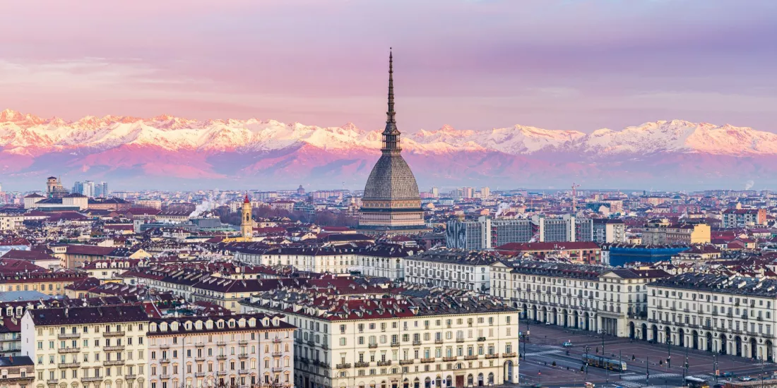 Turyn z wieżą Mole Antonelliana i ośnieżonymi Alpami w tle o wschodzie słońca