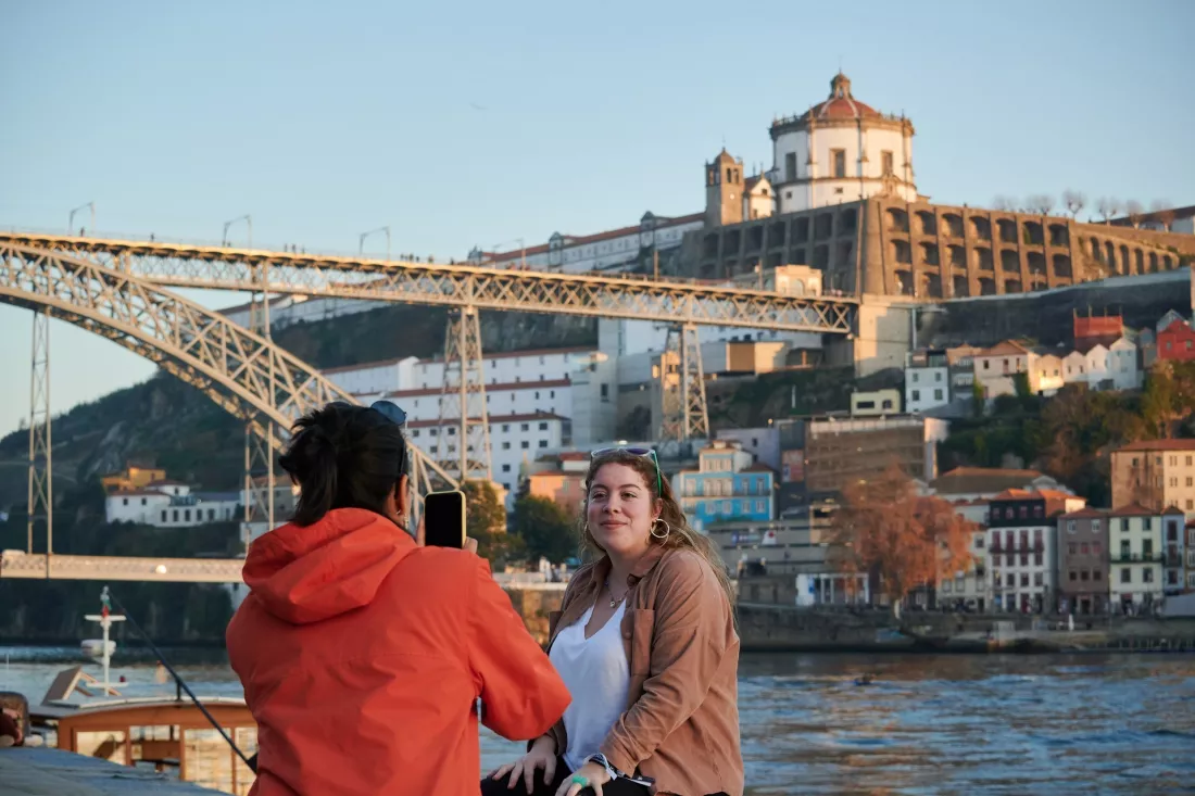 Młoda turystka fotografuje koleżankę nad Duero w Porto, w tle most