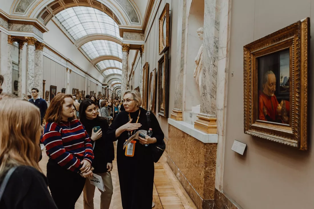 Grupa młodych turystów zwiedza galerię muzeum z przewodniczką
